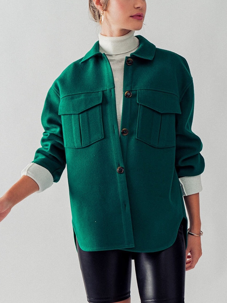 May include: An oversized button-up shirt in a deep green shade, featuring two large pockets on the front. The shirt has a relaxed fit and is made from a soft, comfortable fabric.