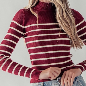 Peut inclure: Un pull &agrave; manches longues ray&eacute; marron et blanc avec un col montant.