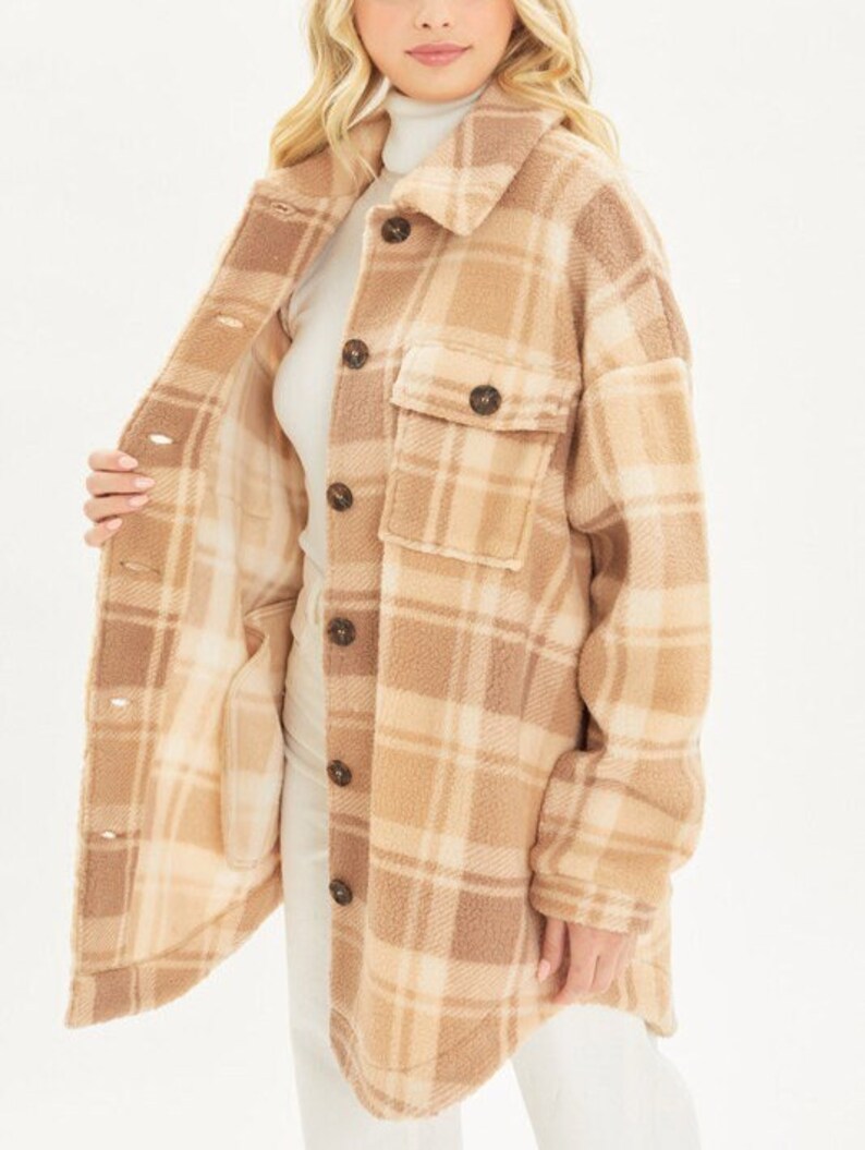 May include: A brown and cream plaid flannel shirt jacket with a soft, fuzzy texture. The jacket has a button-up front and a patch pocket on the chest.