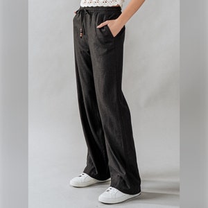 May include: Black wide-leg pants with a drawstring waist and a relaxed fit. The pants are made of a lightweight fabric and have a casual style.