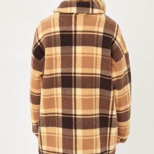 May include: A brown and cream plaid fleece jacket with a long, relaxed fit.