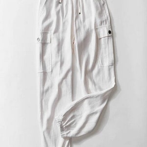 Pode incluir: Calça branca de linho com cintura de cordão e dois bolsos cargo nas laterais.