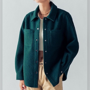 May include: A dark green, long-sleeved, button-up shirt with a textured fabric. The shirt has two large pockets on the front and a collar.