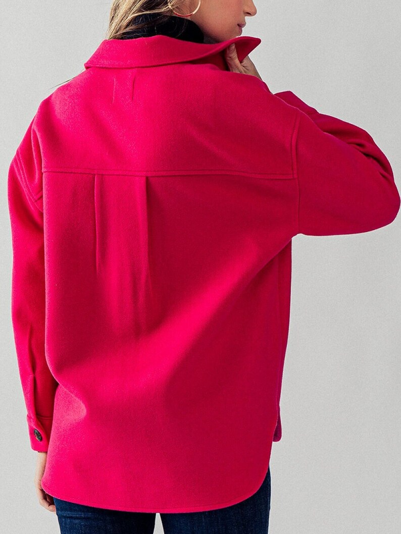 May include: A bright pink, long-sleeved shirt with a collared neckline and button closure. The shirt has a relaxed fit and a slightly longer hemline.
