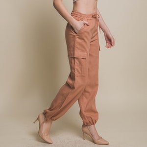 May include: A pair of loose-fitting, light brown cargo pants with a drawstring waist and a single cargo pocket visible on the left leg.