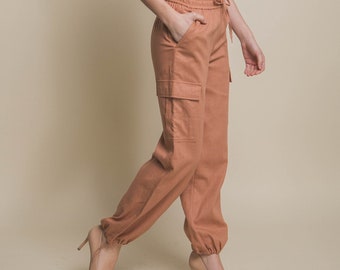 May include: A pair of loose-fitting, light brown cargo pants with a drawstring waist and a single cargo pocket visible on the left leg.