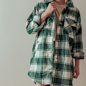 Puede incluir: Una camisa de franela a cuadros verde y blanca con mangas largas y cierre de botones.