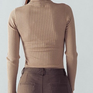 May include: A brown ribbed turtleneck sweater with long sleeves.