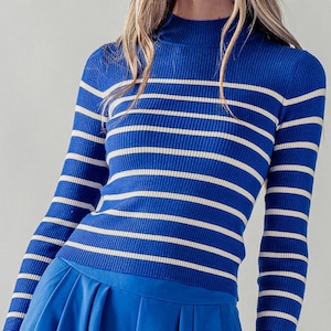 Peut inclure: Un pull &agrave; manches longues bleu et blanc &agrave; rayures avec un col montant.