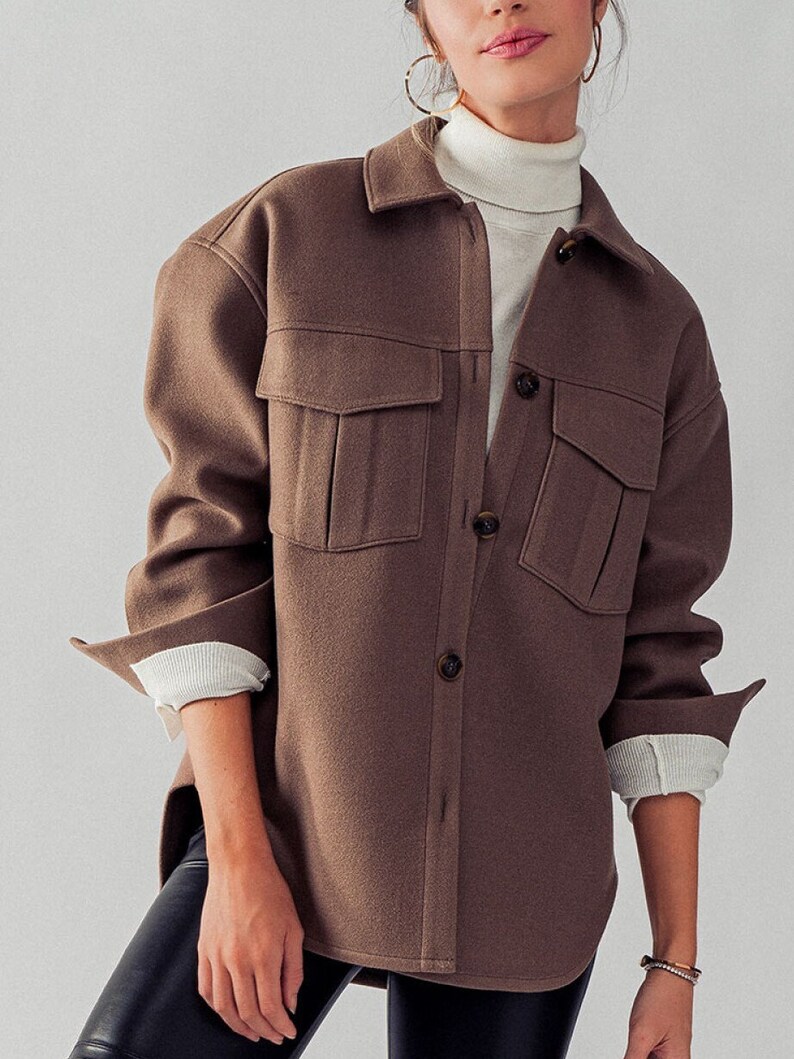 May include: An oversized brown shirt jacket with a button-up front and two large flap pockets. The shirt jacket has a relaxed fit and a slightly longer length.