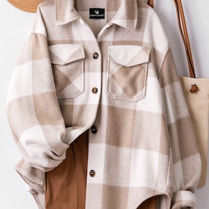May include: A beige and white checked flannel shirt with a button-up front and two chest pockets. The shirt has a label that reads "Urban Daisy".