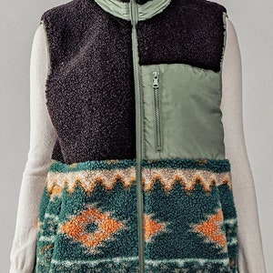 May include: A black, green, and brown patterned fleece vest with a zipper closure. The vest has a high collar and a quilted section on the front.