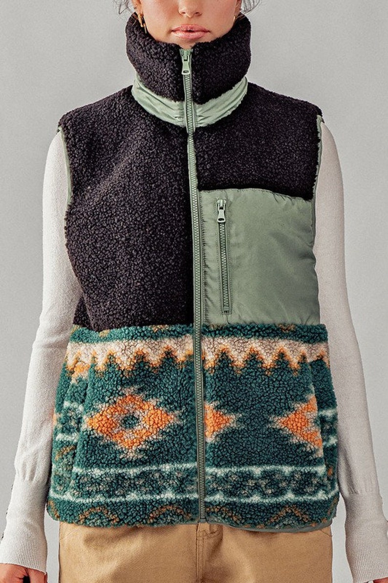 May include: A black, green, and brown patterned fleece vest with a zipper closure. The vest has a high collar and a quilted section on the front.