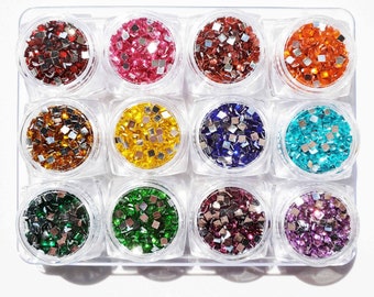 May include: Twelve small jars filled with colourful square rhinestones. The jars are arranged in a grid of four rows and three columns. The rhinestones are in a variety of colours, including red, orange, yellow, green, blue, purple, and silver.
