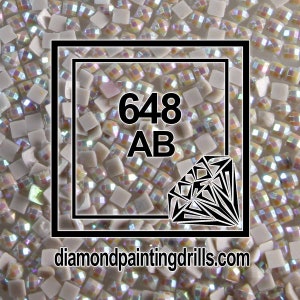May include: Close-up of iridescent white square diamond painting drills with the number 648 AB and the website diamondpaintingdrills.com.