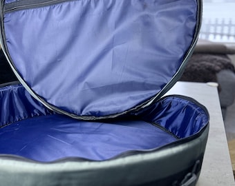 Könnte beinhalten: Eine runde graue und schwarze Tasche mit einem Reißverschluss oben und einem blauen Futter. Die Tasche ist offen und das Futter ist sichtbar.