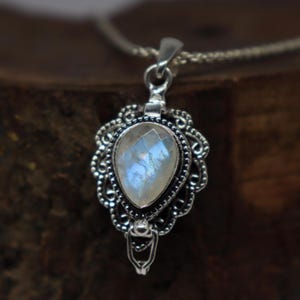 May include: A silver pendant necklace with a pear-shaped moonstone gemstone set in a filigree design.