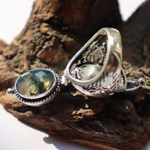 Puede incluir: Un anillo de plata con una piedra de &aacute;gata verde musgo. El anillo est&aacute; decorado con dise&ntilde;os intrincados y tiene un patr&oacute;n de filigrana. La piedra es de forma ovalada y tiene un aspecto natural y org&aacute;nico.