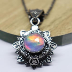 May include: A silver pendant necklace featuring a round, iridescent opal gemstone set within an intricate, ornate silver frame. The pendant is attached to a silver chain.