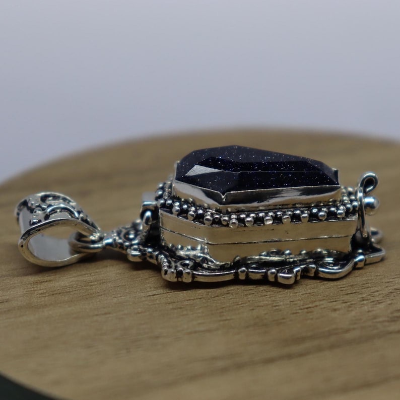 Puede incluir: Colgante de plata con una piedra negra en forma de ata&uacute;d. El colgante tiene un dise&ntilde;o detallado y es perfecto para un estilo g&oacute;tico o espeluznante.