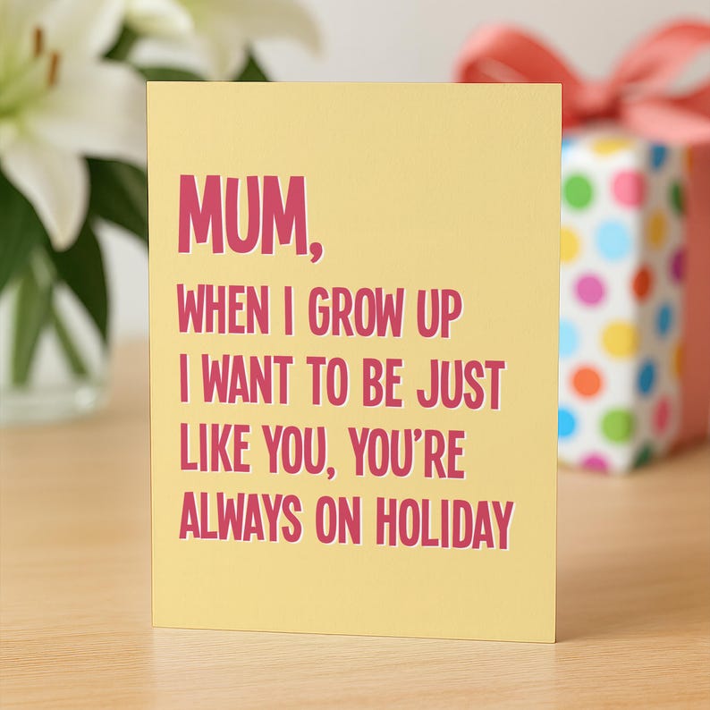 May include: A yellow greeting card with the text "MUM, WHEN I GROW UP I WANT TO BE JUST LIKE YOU, YOU'RE ALWAYS ON HOLIDAY" in pink. A gift box with colorful polka dots and a pink ribbon is in the background.