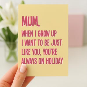 May include: A yellow greeting card with the text "MUM, WHEN I GROW UP I WANT TO BE JUST LIKE YOU, YOU'RE ALWAYS ON HOLIDAY" in pink. The card is held by a person's hand.