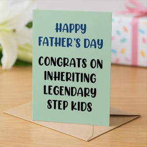 Op de afbeelding: Een Vaderdagkaart met de tekst "Happy Father's Day Congrats on Inheriting Legendary Step Kids" in blauw en zwart op een lichtgroene achtergrond. De kaart zit in een bruine envelop.