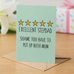 May include: A light green greeting card with the text "EXCELLENT STEPDAD SHAME YOU HAVE TO PUT UP WITH MUM" and five gold stars. The card is on a brown envelope.