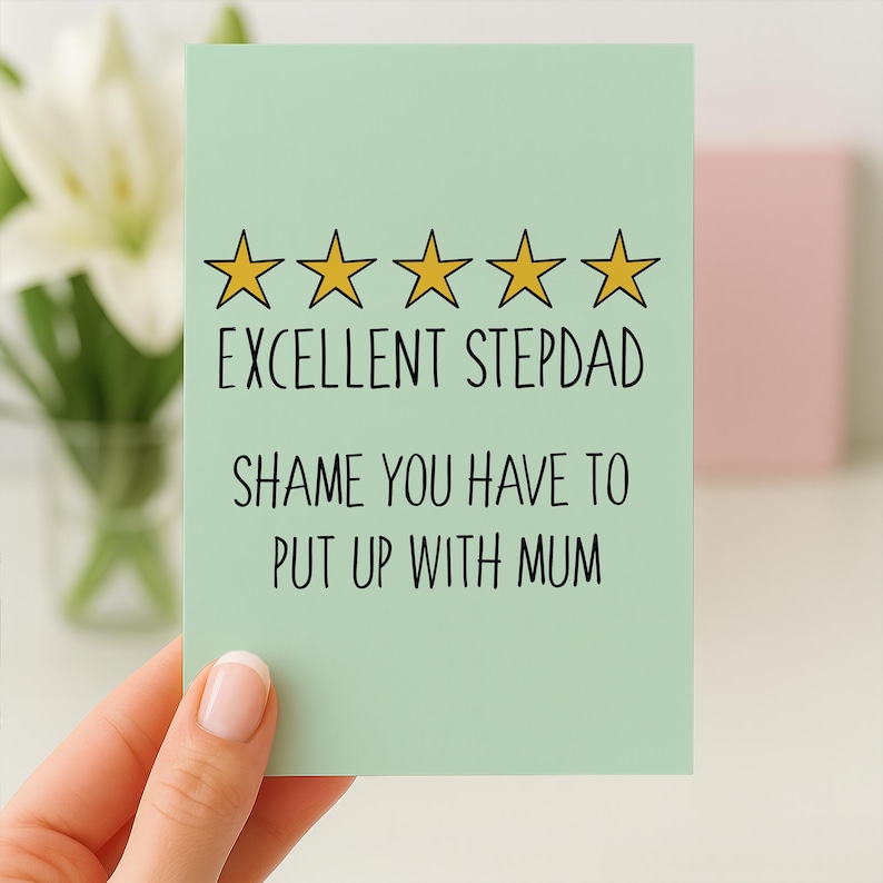 May include: A light green greeting card with the text "EXCELLENT STEPDAD SHAME YOU HAVE TO PUT UP WITH MUM" and five gold stars. The card is held by a person.
