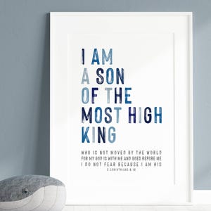 Op de afbeelding: Een ingelijste print met de tekst "I AM A SON OF THE MOST HIGH KING" in blauwtinten. Een grijze walvisknuffel ligt voor het frame. De print bevat een Bijbelvers.