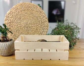 Puede incluir: Una caja de madera natural con un acabado de madera clara. La caja está vacía y tiene una forma rectangular. La caja está sentada sobre una superficie de madera.