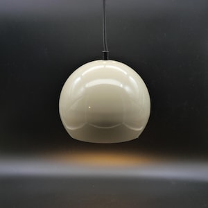 May include: Cream-colored, spherical pendant light fixture. The light has a glossy finish and is suspended from a black cord. The fixture is a simple, modern design, suitable for various interior styles.