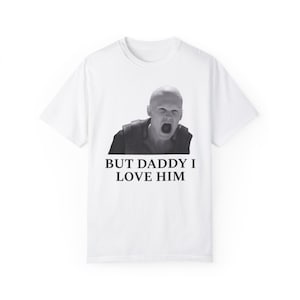 May include: White t-shirt with a black and white image of a bald man yelling. The text "BUT DADDY I LOVE HIM" is printed below the image.