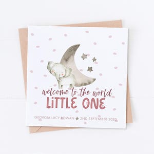 May include: A white card with a pink and gray elephant illustration standing on a crescent moon with stars. The text reads "welcome to the world LITTLE ONE GEORGIA LUCY ROWAN 2ND SEPTEMBER 2020".