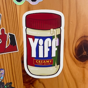 May include: A white sticker with a cartoon image of a jar of creamy, white spread with a red lid. The jar has the word "Yiff" in large, white letters on a blue and green background. The label reads "Creamy Furry Batter".