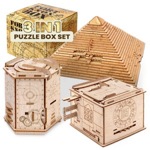 Könnte beinhalten: Ein Set aus drei Holz-Puzzleboxen. Die Boxen sind aus Naturholz gefertigt und haben komplizierte Designs. Das Set enthält eine pyramidenförmige Box, eine zylindrische Box und eine quadratische Box. Die Boxen sind mit "3 in 1 Puzzle Box Set" beschriftet.