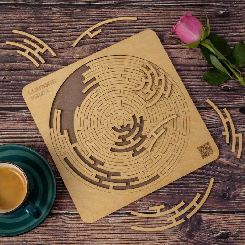 May include: A wooden labyrinth puzzle with a circular design. The puzzle is made of brown wood and has a light brown background. The puzzle is called "Labyrinth Puzzle" and is made of wood.
