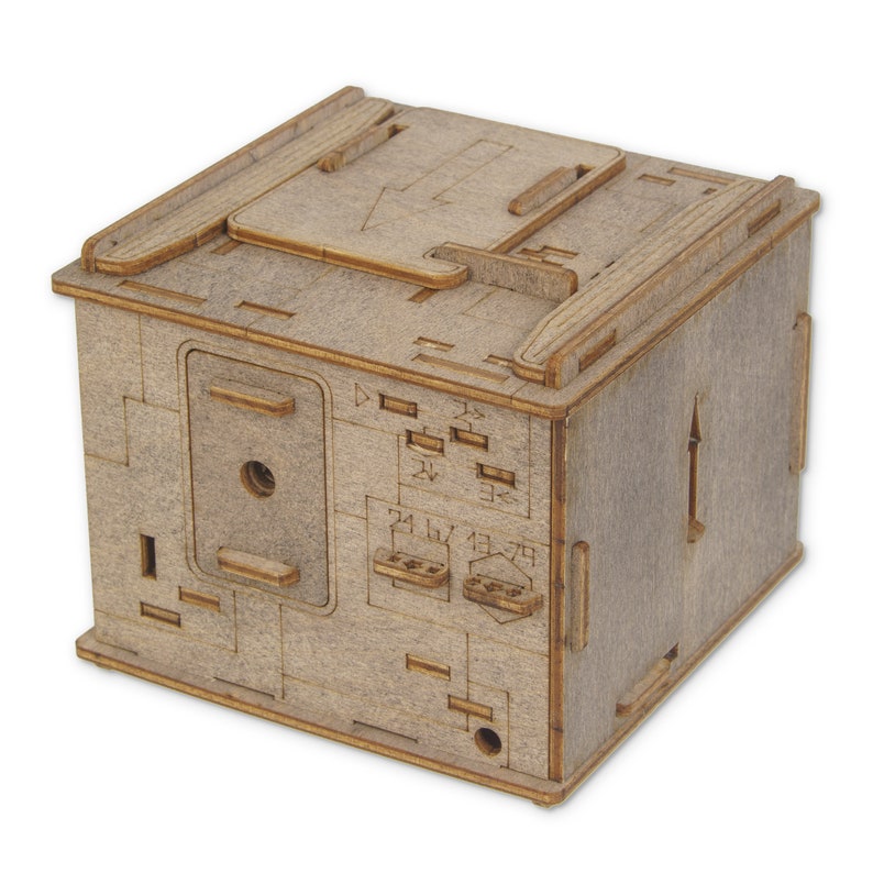 May include: A wooden box with a hinged lid and a small hole in the front. The box has a number of small slots and markings on the front and sides. The box is made of light brown wood and has a natural finish.