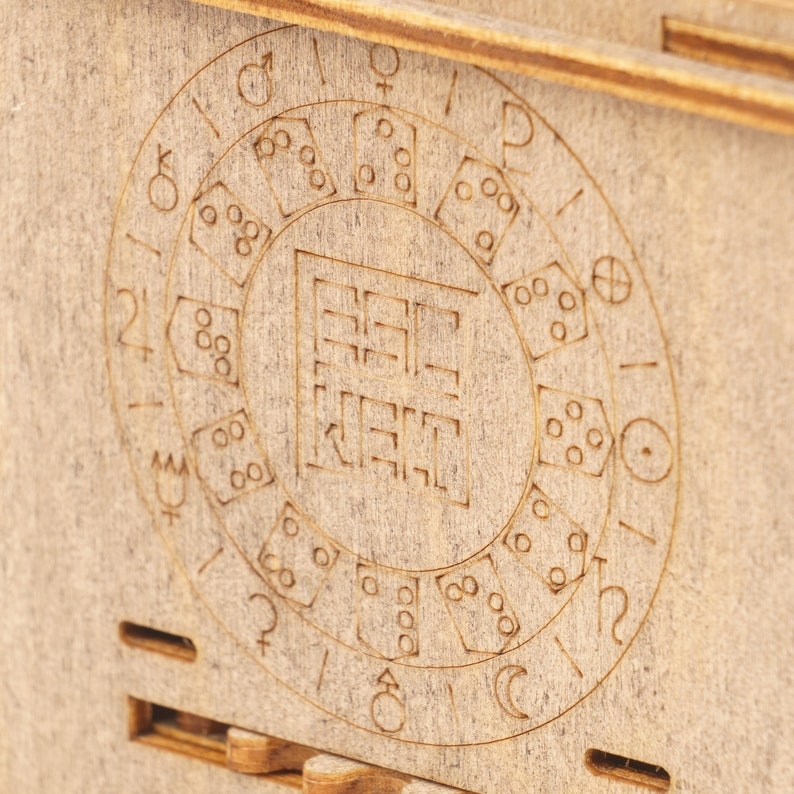May include: Close-up of a wooden box with a circular design featuring dice and astrological symbols. The center of the design has a square with the text "REIKI" inside.