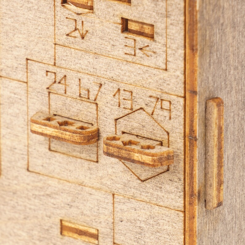May include: Close-up of a wooden box with two small wooden levers. The levers are labeled with the numbers 24, 67, 13, and 79.