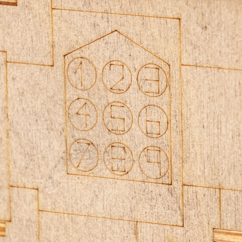 May include: A wooden board with a house-shaped design featuring a number pad with the numbers 1 through 9.