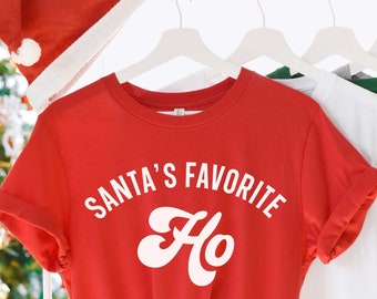 May include: Red t-shirt with white text that says "Santa's Favourite Ho" in a retro font.