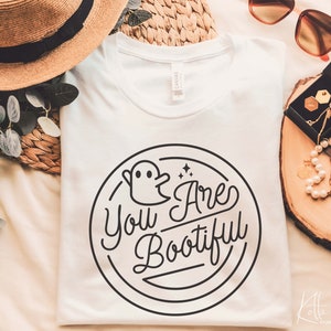 May include: White t-shirt with a black and white graphic design of a ghost and the text "You Are Bootiful".