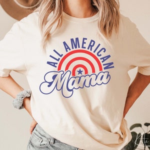 May include: A white t-shirt with a blue and red graphic that says "All American Mama" with a red, white, and blue star design.