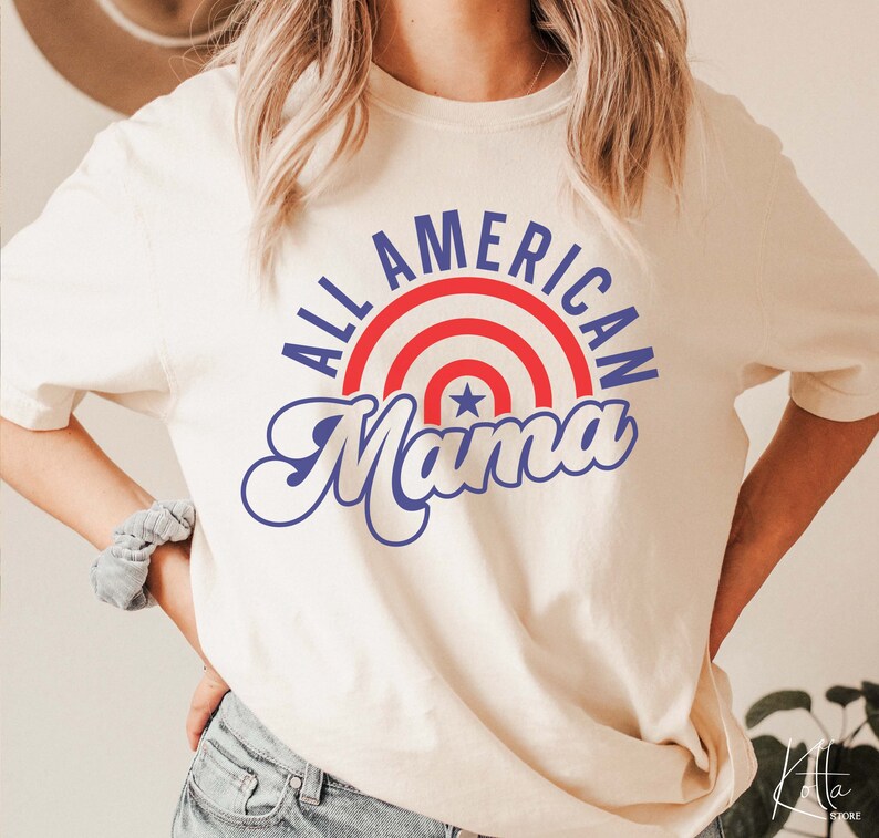 May include: A white t-shirt with a blue and red graphic that says "All American Mama" with a red, white, and blue star design.