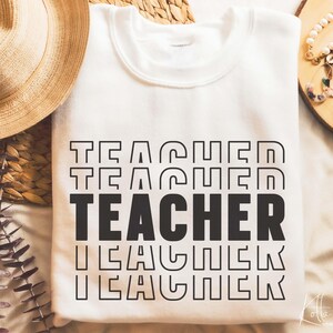 Puede incluir: Sudadera blanca con la palabra "TEACHER" repetida cinco veces en una fuente de estilo retro. La palabra "TEACHER" est&aacute; en negro y la fuente est&aacute; delineada en negro.