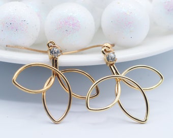 May include: A pair of gold-tone earrings with a delicate leaf design and a clear rhinestone in the center of each earring.