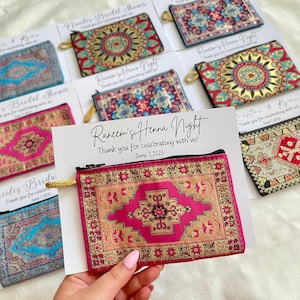 May include: Several small, rectangular fabric pouches with zip closures, adorned with detailed rug-style patterns in diverse colours. The pouches are presented with cards that read "Raneem's Henna Night" and "Thank you for celebrating with us!"