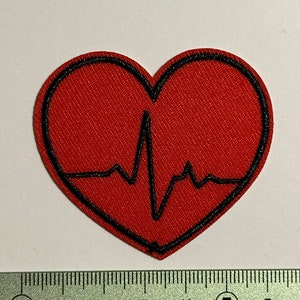 May include: Red heart-shaped patch with a black outline and a black EKG line inside. The patch is approximately 5 cm wide.