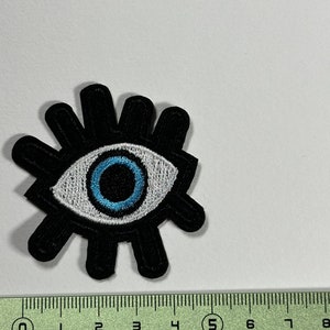 Peut inclure: Patch brodé noir avec un motif d'œil blanc et bleu. Le patch mesure environ 5 cm de diamètre.